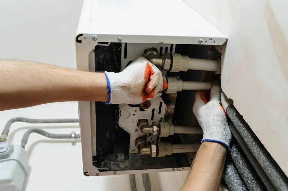 Qualified heating engineer installing a new energy-efficient boiler and connecting the central-heating pipework in a home