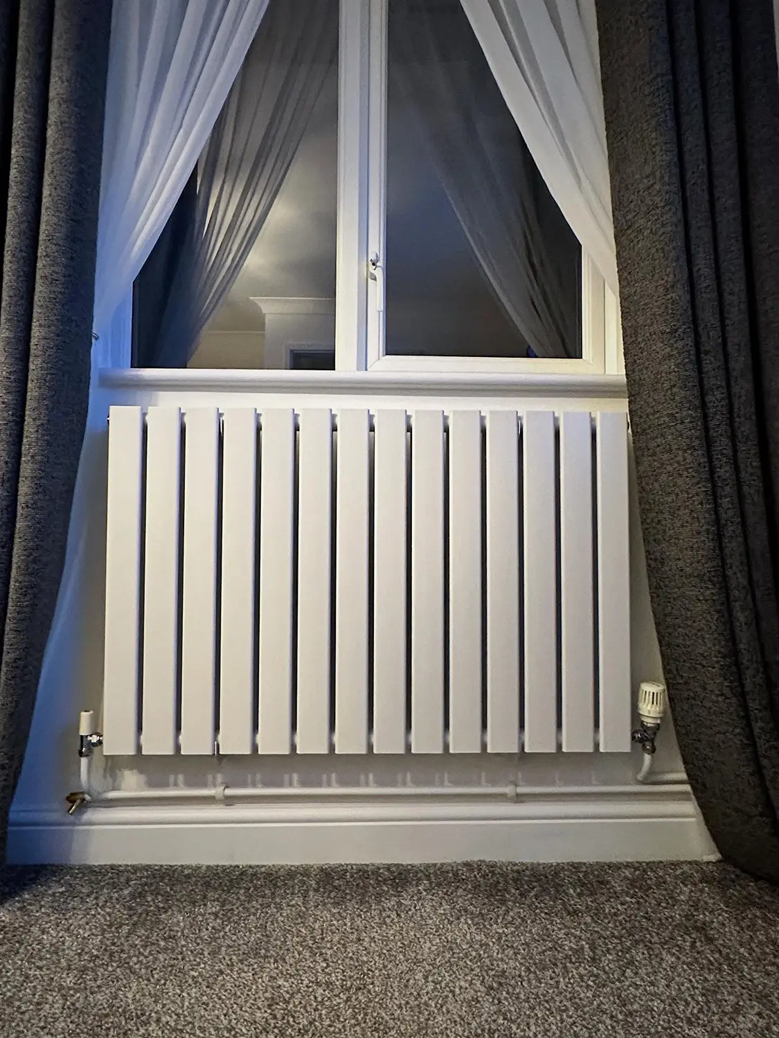 Clean modern vertical slatted radiator fitted in a contemporary home interior by J. Copland